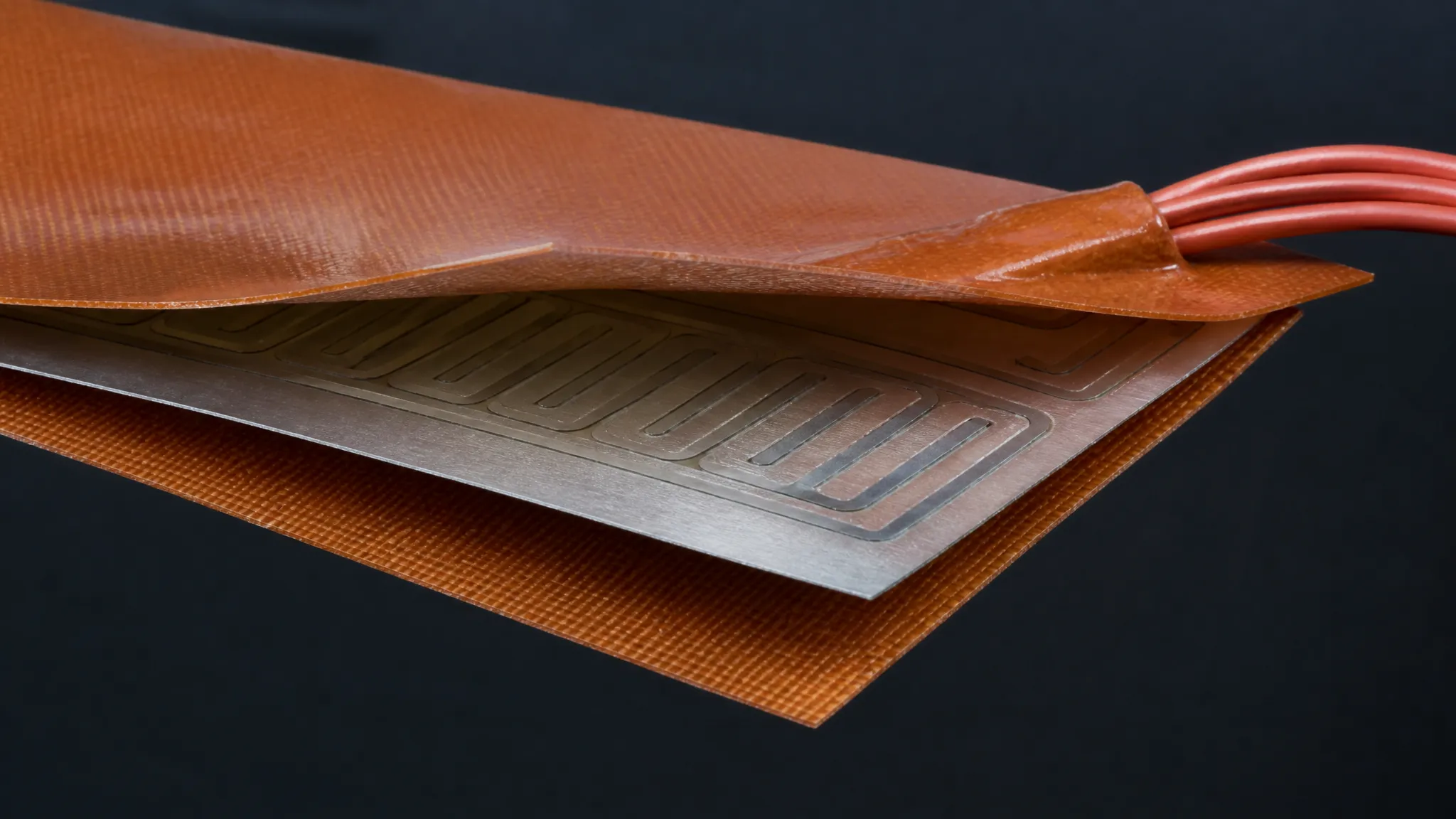 Exploded view of a flexible silicone heater pad showing the fiberglass-reinforced silicone layers sandwiching the heating element