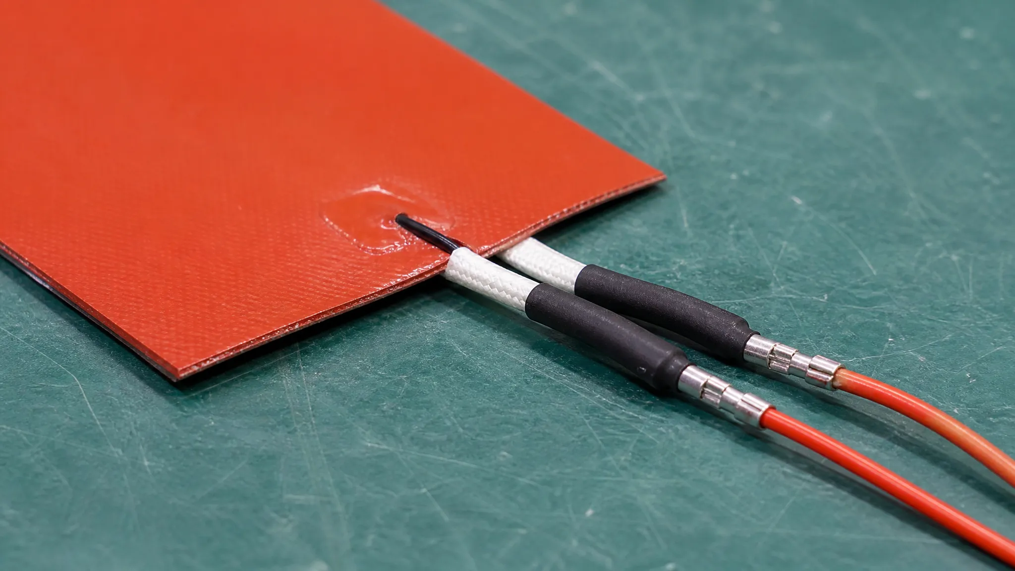 A silicone heater pad assembly with an integrated NTC sensor and lead termination laid out for inspection